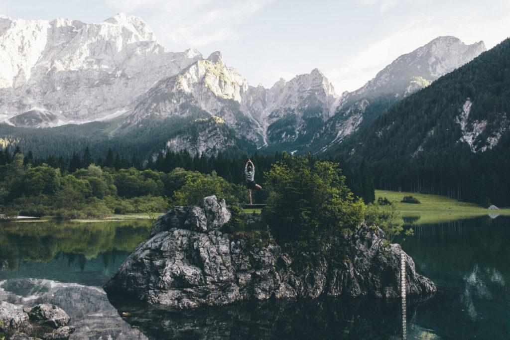 person standing on rock formation surrounded by body of water